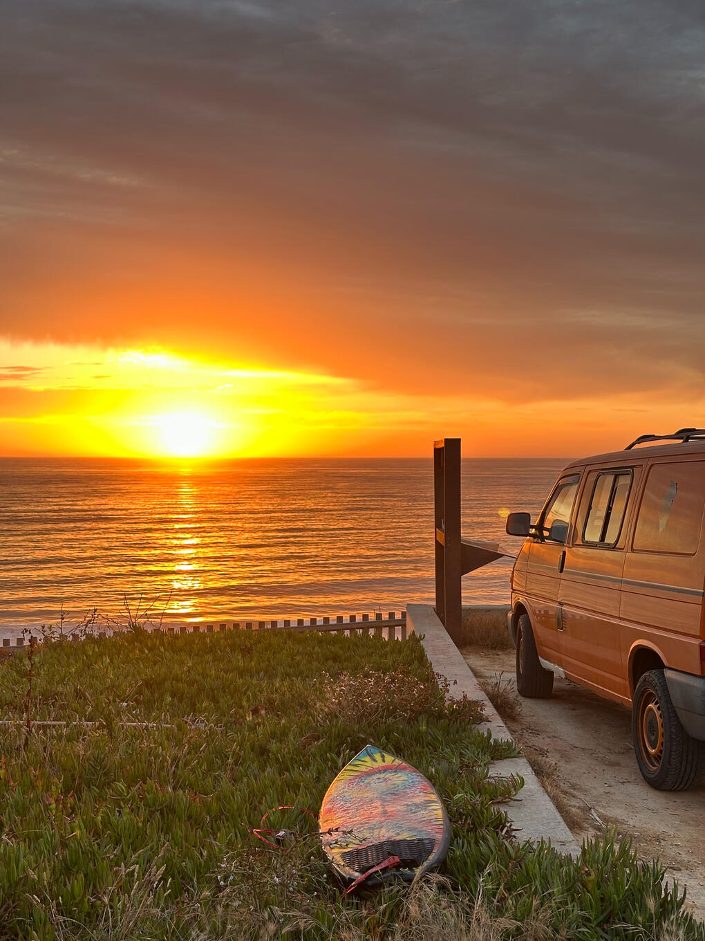 ocean sunset with a van and a surfboard