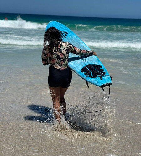surfergirl walking in waves with surfboard