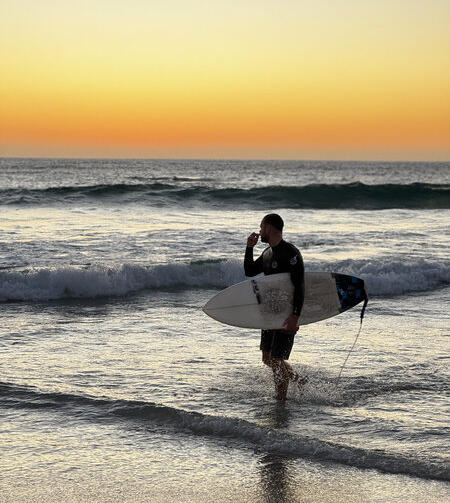 surfer with surboard in front of ocean sunset