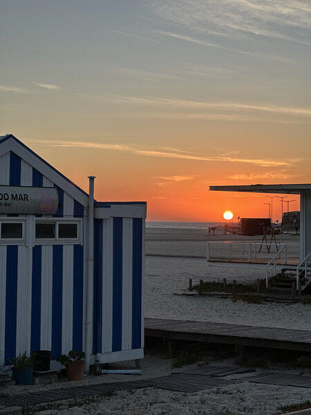 sunset on the beach with blue and white beach house