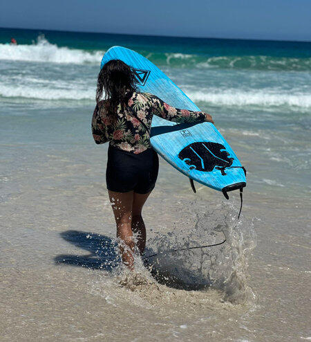 surfergirl with surboard in front of ocean sunset